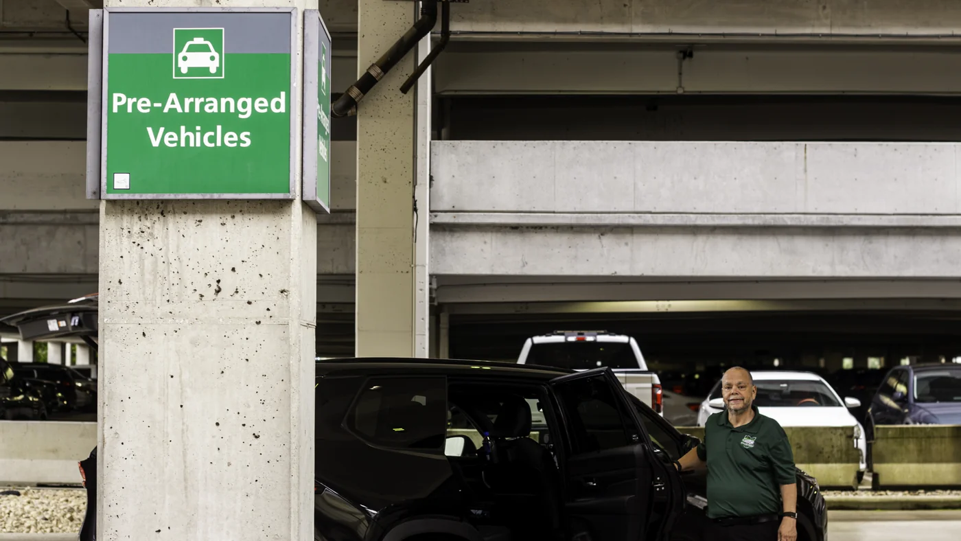 Steve beside the Pre-Arranged Vehicles sign at CMH